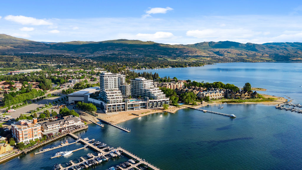 Daytime aerial view of Aqua Waterfront Village, its beach, boardwalk and marina on Okanagan Lake